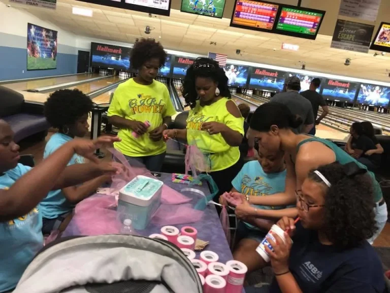 Girls and mentors working at a table during a bowling outing