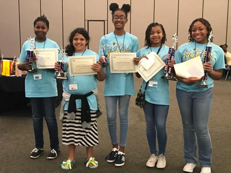 Girls holding the certificates and trophies they were awarded