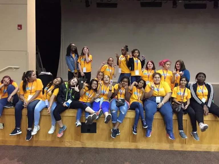 Girls in program shirts seated together at an event