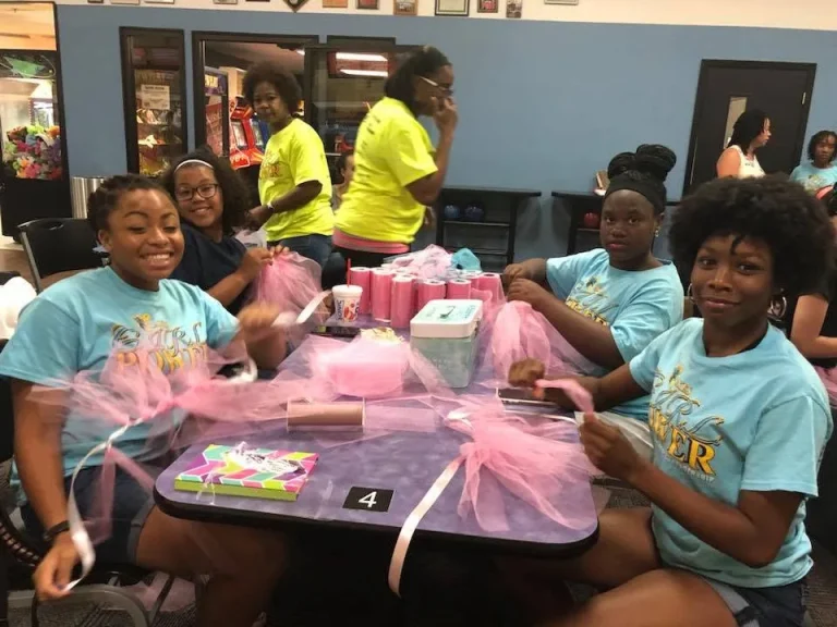 Girls assembling a craft project at a decorated table