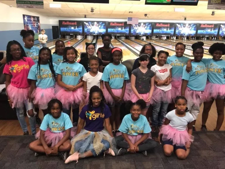 A group of girls in program shirts and tutus pose together
