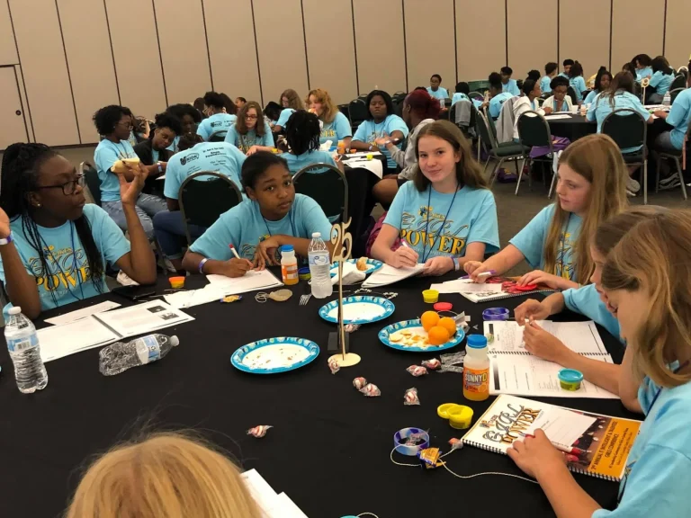 Girls working through a hands-on activity at a workshop table