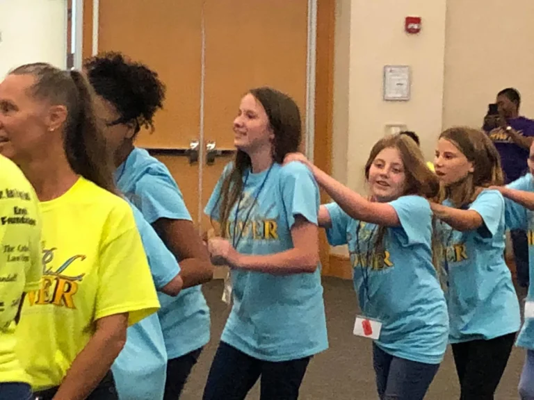A mentor guides a line of girls through a team activity