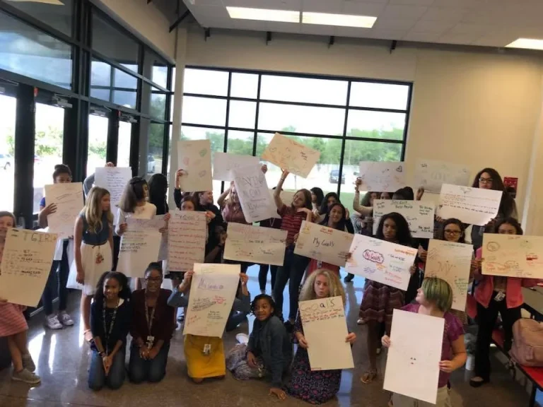 Girls present their finished poster boards to the room