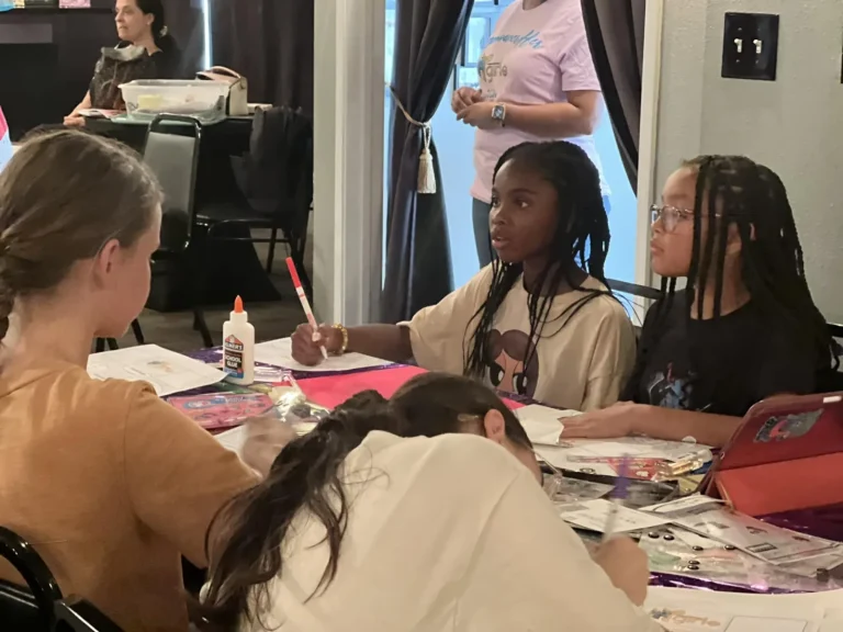 Girls cutting and arranging images for a collage project
