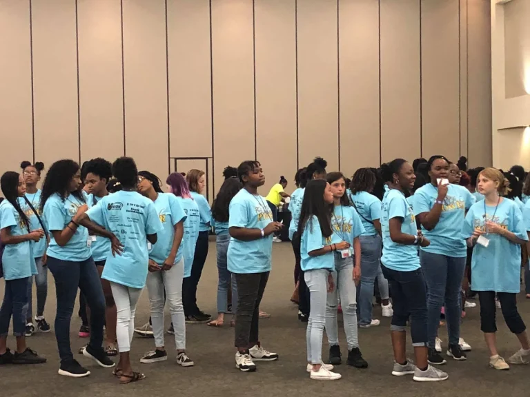 Girls in matching program shirts gathering at the start of a workshop day